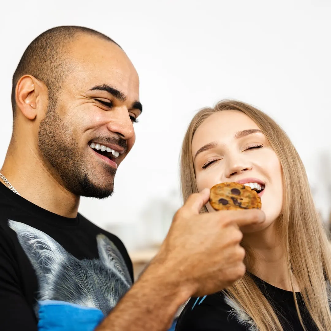A man and a woman eating Baked Delta-9 Chocolate Trip Cookies.