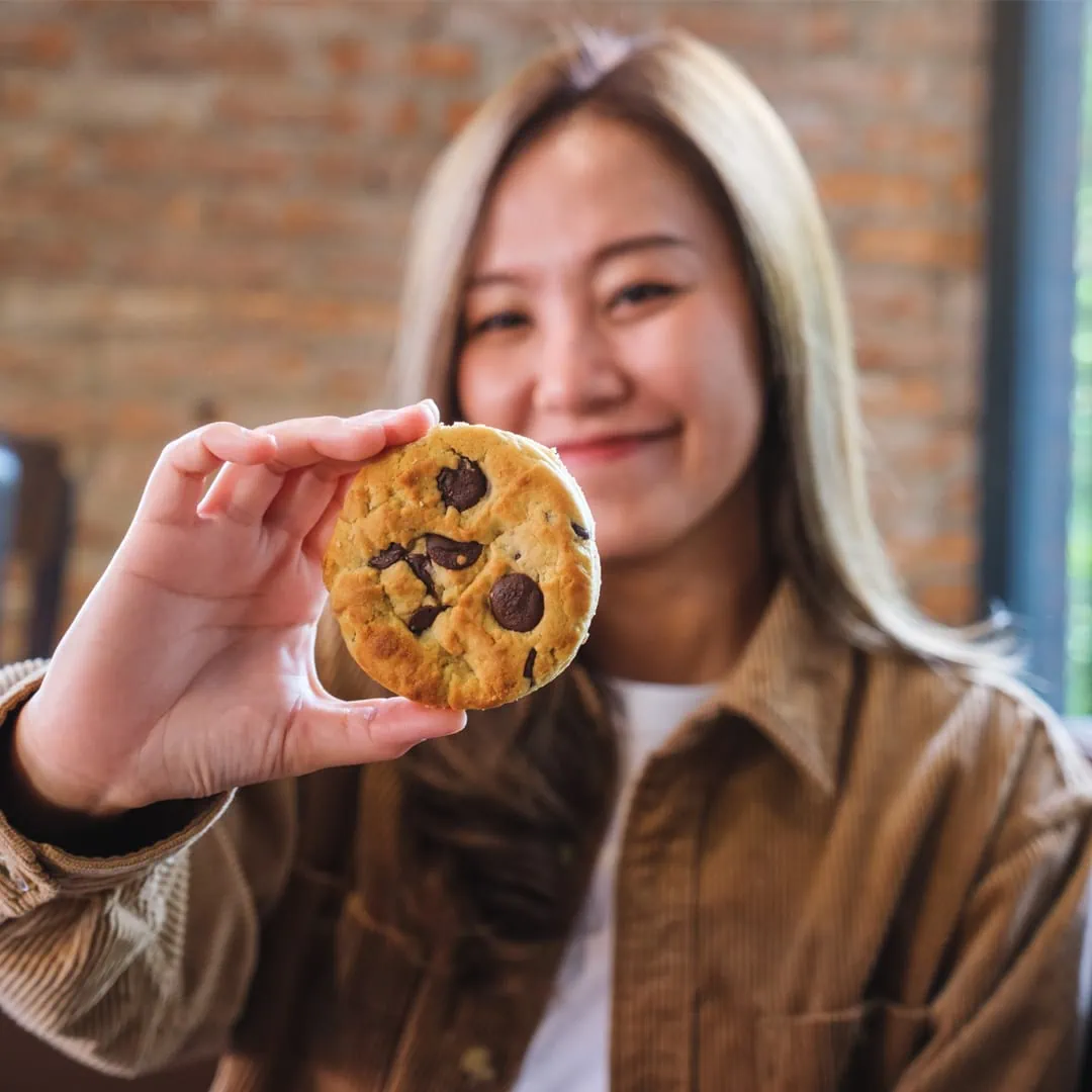 A woman holding up a baked Delta-9 Chocolate Trip cookie.
