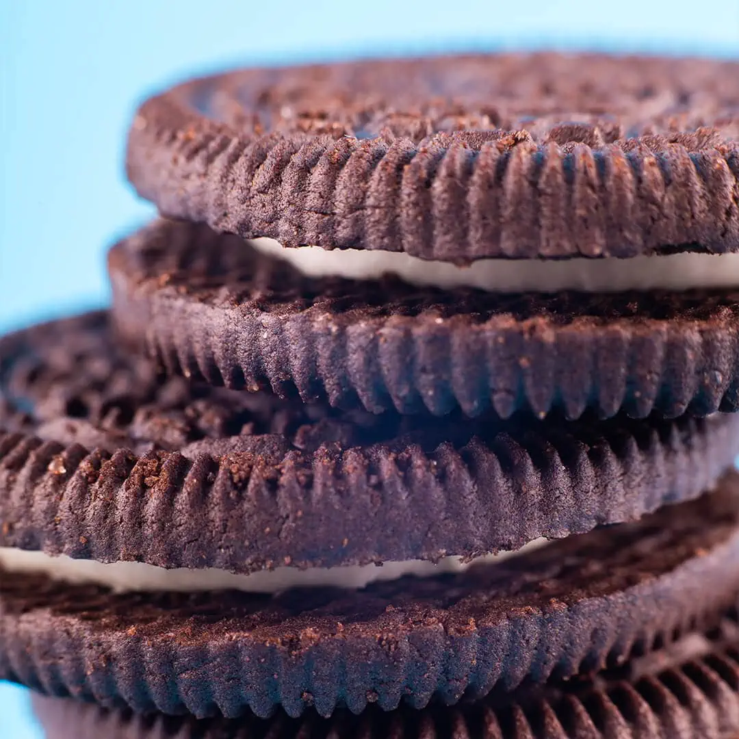 A stack of Baked Delta-9 Magic Brownie Oreo cookies on a blue background.