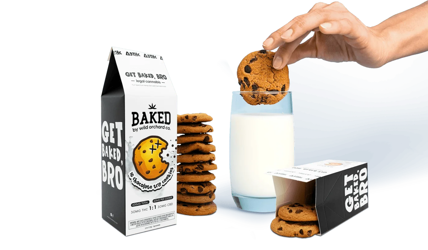 A person holding a glass of delta 8 milk next to a box of cookies.